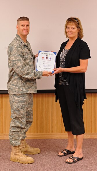 Lt. Col. Kevin Seeley, 7th Medical Support Squadron commander, presents Mrs. Patty Williams, 7th Medical Group, with the September MDG superior performer award, Oct. 13, 2011, at Dyess Air Force Base, Texas. Every month each group selects a person or team who has shown superior performance to be recognized in front of wing leadership. (U.S. Air Force photo by Airman 1st Class Peter Thompson/Released)