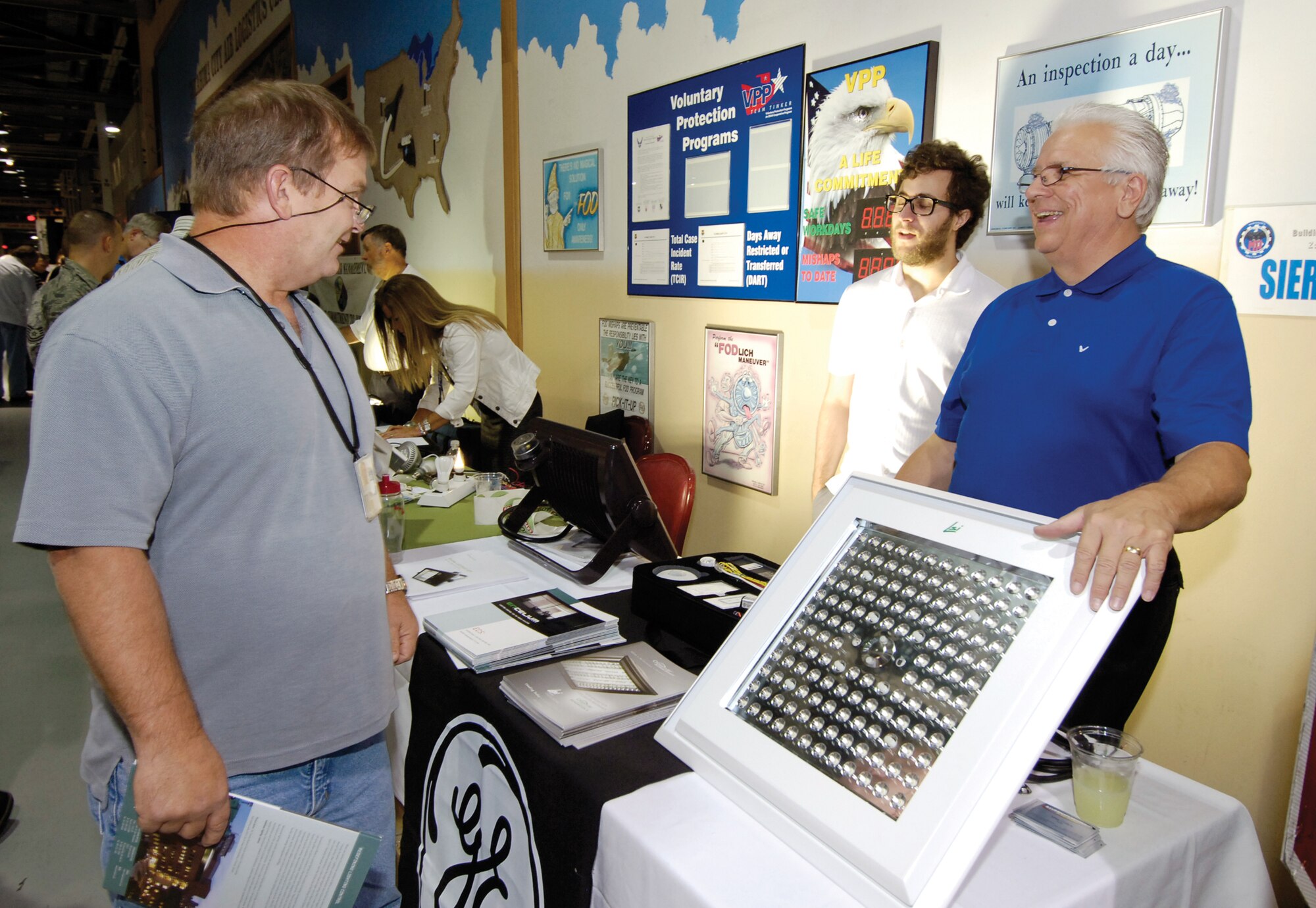 James Ike, an aerospace engineer in the Oklahoma Air Logistics Center Propulsion Sustainment Division, stops at a booth showing energy-saving LED high-bay light fixtures.  The lights, says representative Mike Collins, right, use 120 watts versus the 454 watts of some lights and eliminate infrared and ultraviolet rays we don’t see, saving energy and giving people a better light to see by.  Energy savings devices and tips were offered Oct 6 during the Energy Expo in Bldg. 3001 near Hollywood and Vine and sponsored by the 72nd Air Base Wing Civil Engineer Directorate.  (Air Force photo by Margo Wright)