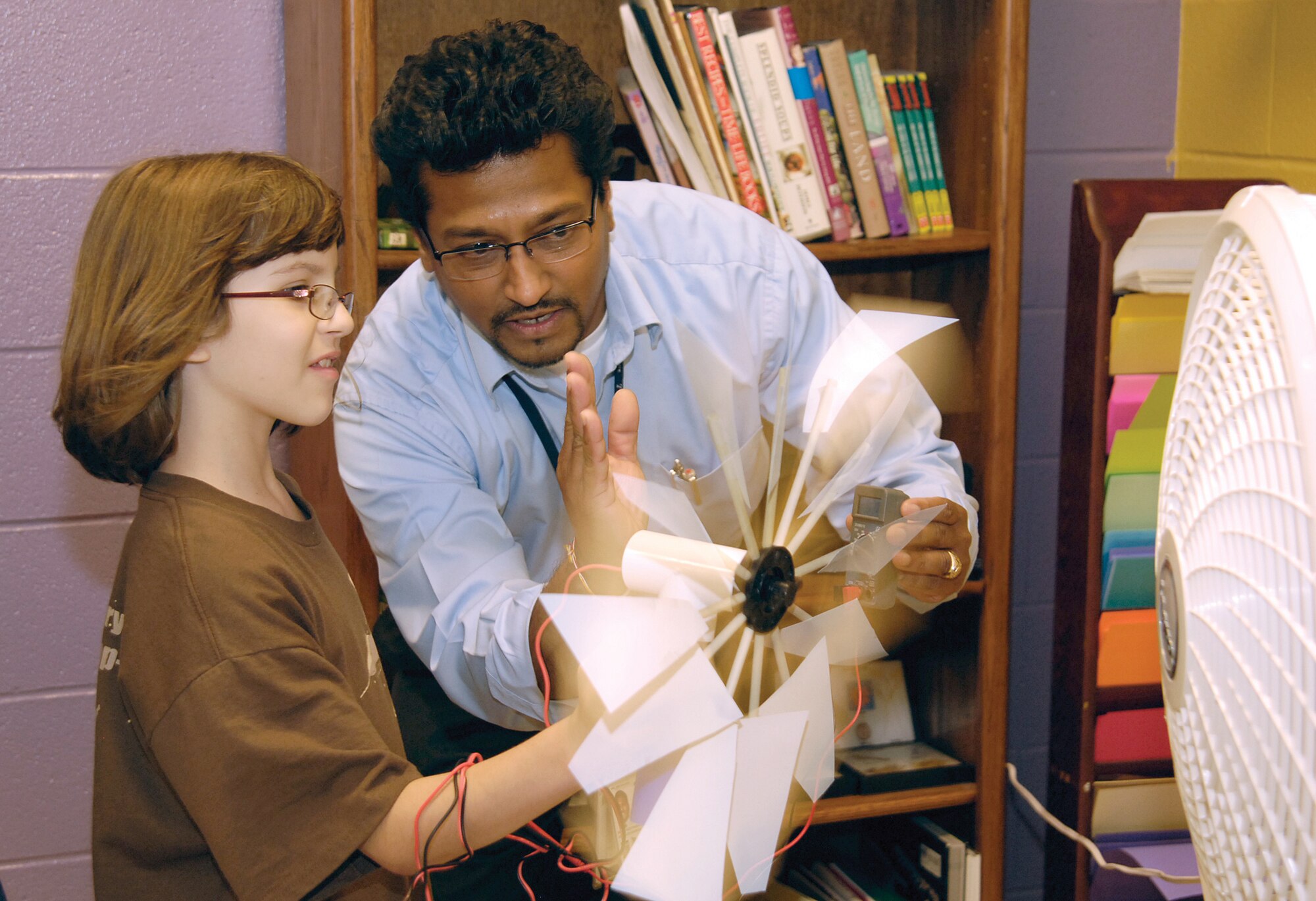 Aruna Abhayagoonawardhana, 76th Aircraft Maintenance Group mechanical engineer, huddles with Tinker Youth Center fifth-grader Ashley Schatzle to test the energy output of a home-made wind turbine.  Kids grouped with Tinker engineers and 72nd Air Base Wing Civil Engineer Directorate Base Resource volunteers to build, test and tweet the performance of their creations during an Oct. 5 4-H National Science Experiment held at the youth center. (Air Force photo by Margo Wright)