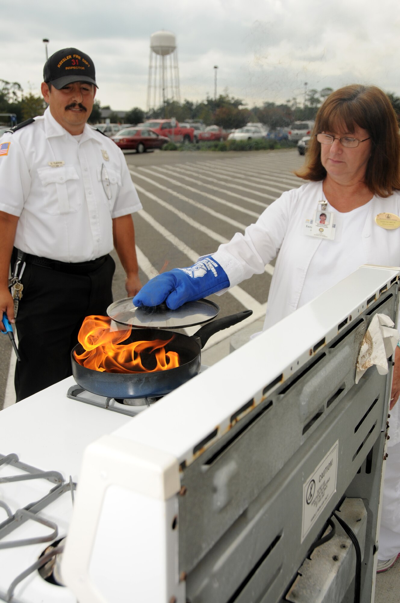 David Tijerina, 81st Infrastructure Division fire inspector, instructs Kendall Diaz, Air Force retiree, on how to safely put out a grease fire at a display in front of the base exchange, Keesler Air Force Base, Miss., Oct. 11, 2011.  Fire Prevention week is Oct. 11-15.  (U.S. Air Force photo by Kemberly Groue)