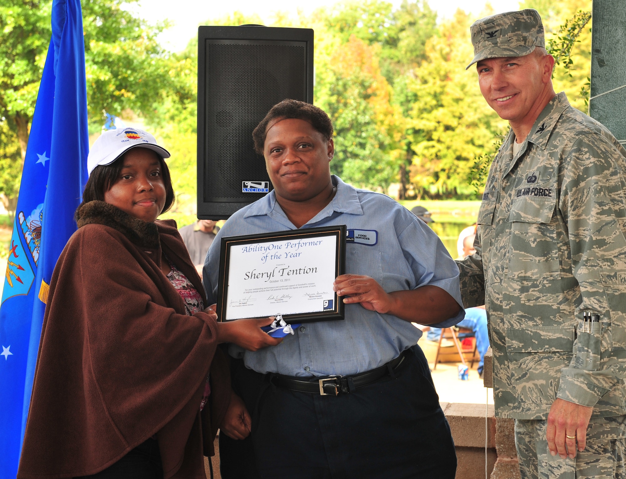 Melissa Simmons, Goodwill employment specialist, and U.S. Air Force Col. Scott Kiser, Air Combat Command chief of contracting, presents Sheryl Tention, Goodwill employee, with an AbilityOne Performer of the Year award during the AbilityOne appreciation picnic at the Memorial Lake pavilion at Shaw Air Force Base, S.C. Oct. 13, 2011. The 12th annual AbilityOne appreciation picnic was held in support of National Disability Employment Awareness Month at Shaw. (U.S. Air Force photo by Airman 1st Class Amber E. N. Jacobs/Released)