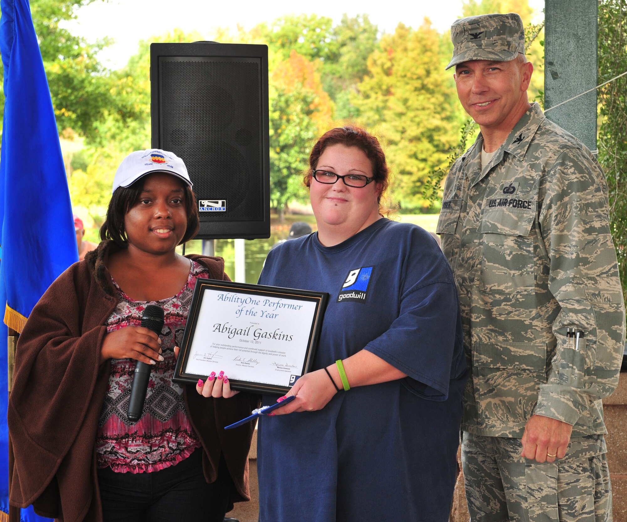 Melissa Simmons, Goodwill employment specialist, and U.S. Air Force Col. Scott Kiser, Air Combat Command chief of contracting, presents Abigail Gaskins, Goodwill employee, with an AbilityOne Performer of the Year award during the AbilityOne appreciation picnic at the Memorial Lake pavilion at Shaw Air Force Base, S.C. Oct. 13, 2011. AbilityOne provides jobs to workers with disabilities while allowing employers to compete in today's global economy. (U.S. Air Force photo by Airman 1st Class Amber E. N. Jacobs/Released)