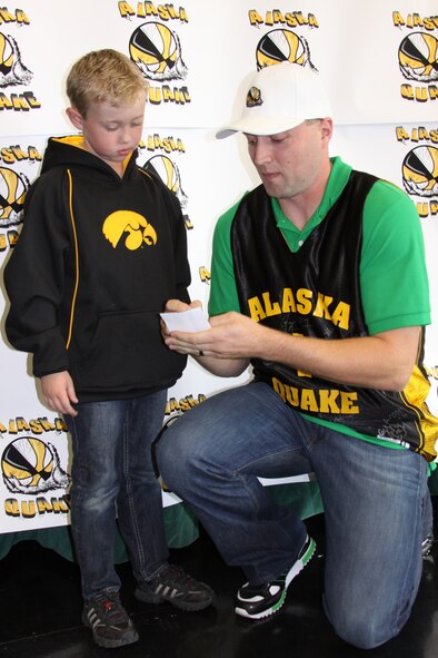 Master Sgt. Jonathon Orzechowski, a Reservist with the 477th Civil Engineer Squadron, signs an autograph for Kelby Therrien during the Alaska Quake meet and greet at Begich Middle School Oct. 8. Sergeant Orzechowski was one of 20 players who made the roster for Alaska's newest semi-professional basketball team. (U.S. Air Force Photo/ Capt. Ashley Conner) 