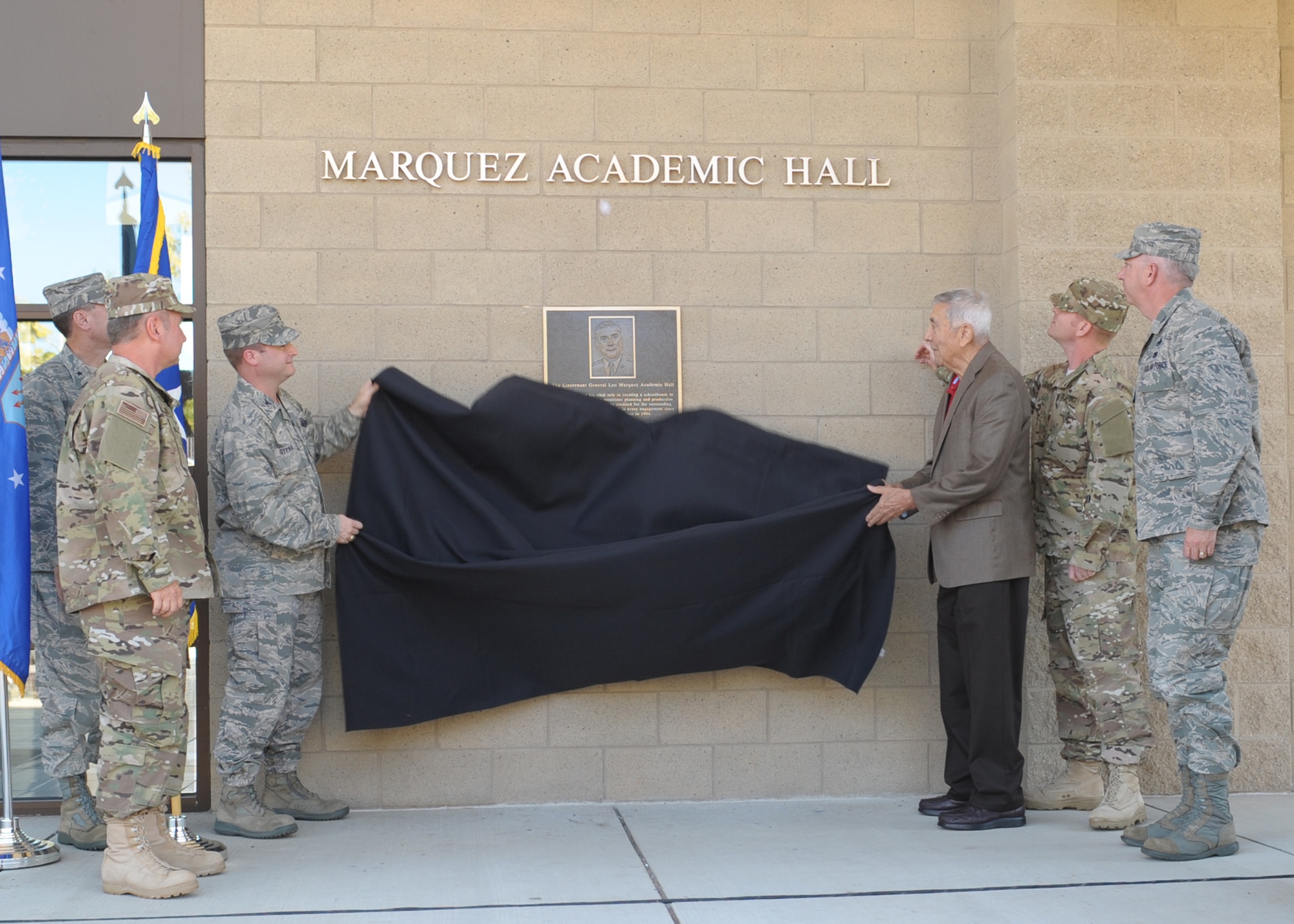 (Left) Col. Phillip Stewart, 9th Reconnaissance Wing vice commander, assists (right) retired Lt. Gen. Leo Marquez, founder of the Air Force Combat Ammunition School, unveil the dedication plaque of the school’s main building renaming it to Marquez Academic Hall. The dedication was part of AFCOMAC’s 25th Anniversary celebration. (U.S. Air Force photo by Mr. John Schwab)