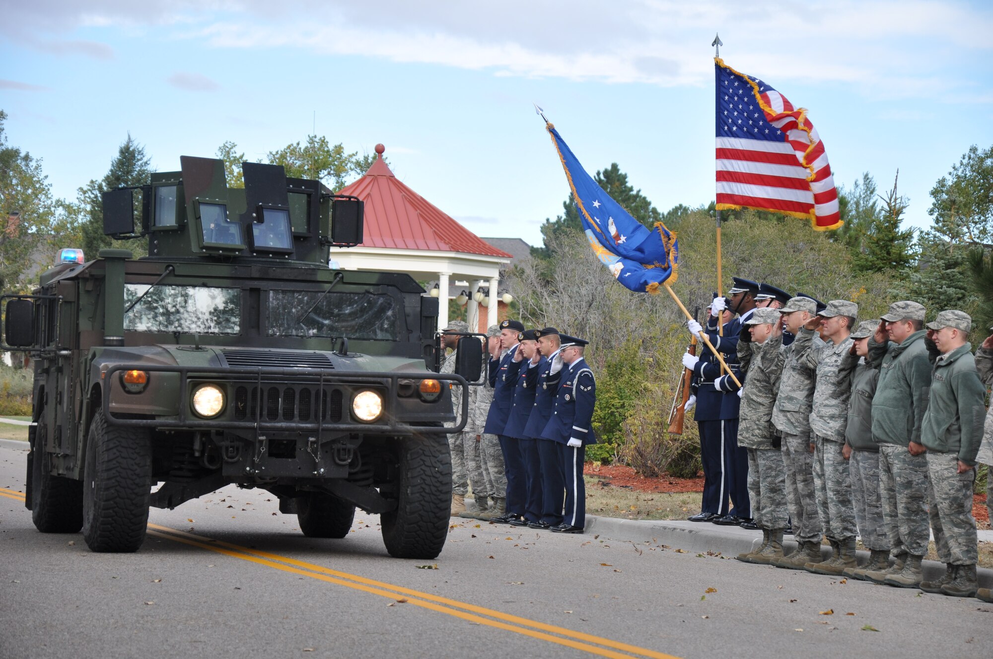 Warren’s honor guard presents the colors as a HMMWV drives by on Ft. Warren Avenue Oct. 11. Mighty Ninety members aligned the streets of Warren to pay respect to the World War II veterans participating in the final Honor Flight. (U. S. Air Force photo by Airman 1st Class Dan Gage)