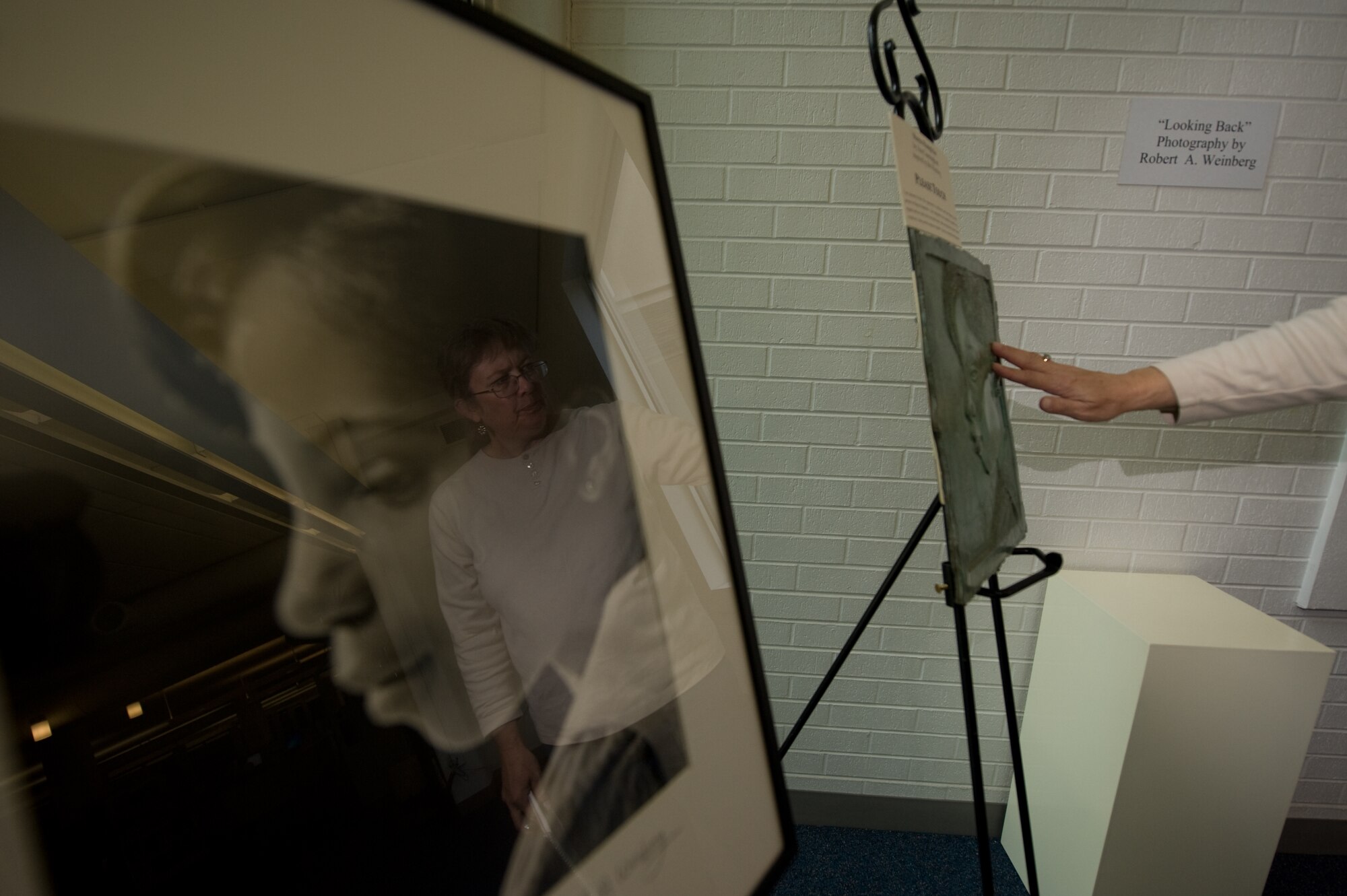 DENVER, Colo. -- Janet Watkins touches a sculpture of Shayna Humphries by Ann Cunningham Sept. 20, 2011.  Cunningham created the statue to honor Robert Weinberg, a local Denver photographer who lost his sight.  This sculpture allows the visually impaired enjoy the portrait originally taken by Weinberg, seen on the left.  (U.S. Air Force photo by Airman 1st Class Phillip Houk)