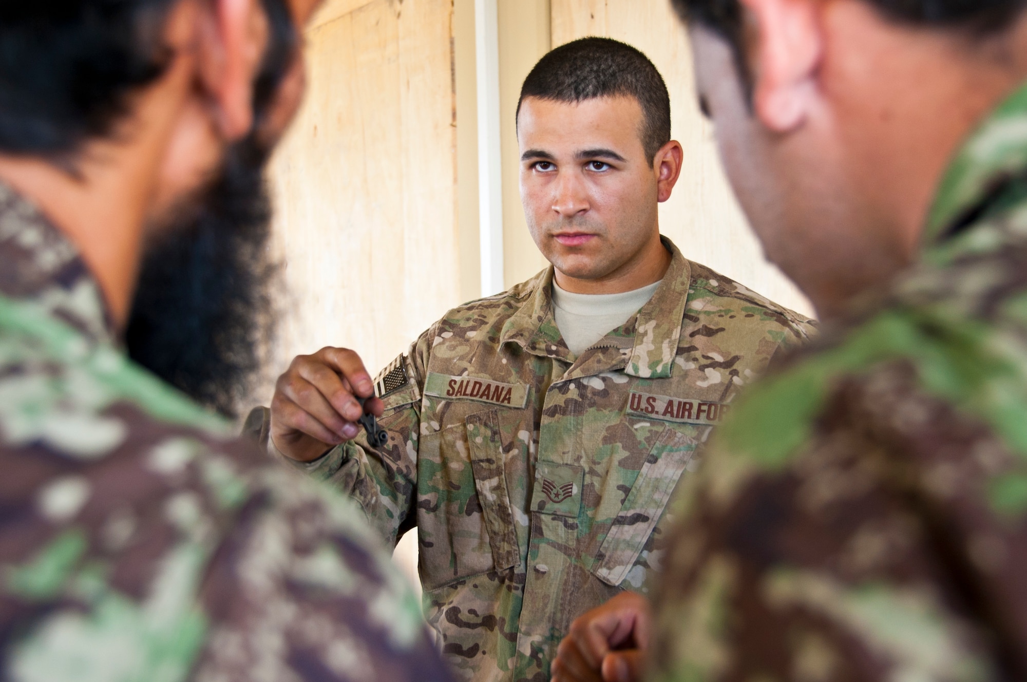 KANDAHAR AIRFIELD, Afghanistan -- Staff Sgt. Mark Saldana, 451st Expeditionary Security Forces Squadron Combat Arms Training and Maintenance, shows members of the Afghan air force a component of the lower assembly of an M-16 during a training session Oct. 13 at Kandahar Air Wing. Saldana is deployed from Joint Base San Antonio, Texas, and is a San Antonio native. (U.S. Air Force photo by Senior Airman David Carbajal)