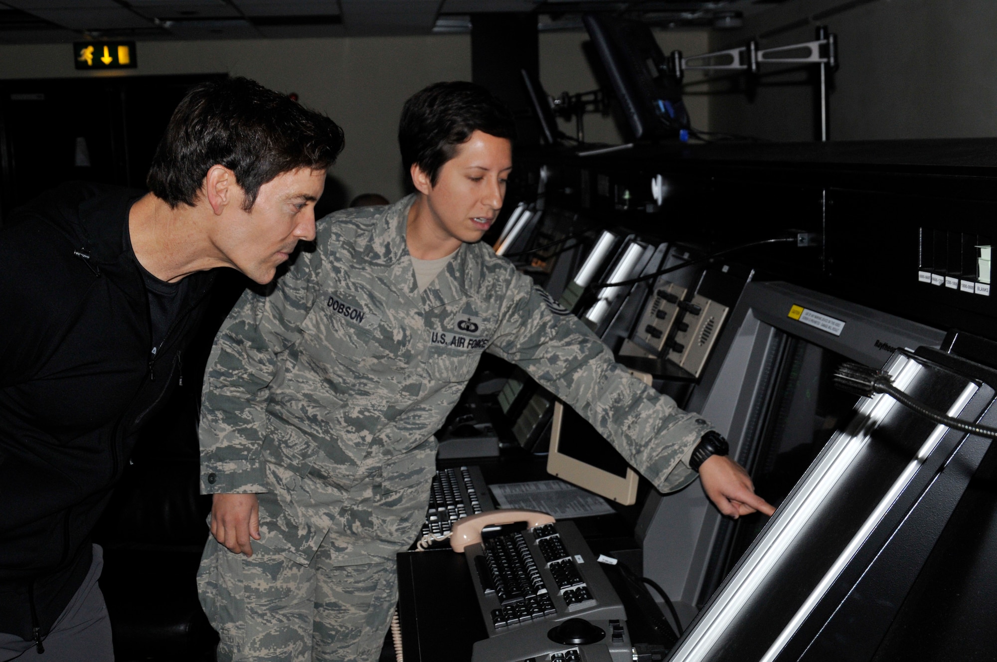 ROYAL AIR FORCE LAKENHEATH, England - Tech. Sgt. Kristin Dobson, 48th Operational Support Squadron Air Traffic Control watch supervisor, describes the Standard Terminal Automation Replacement System to fitness guru Tony Horton in the Radar Approach Control facility Oct. 13, 2011. Horton brought his P90X workout to Lakenheath as part of his Ripped and Ready Tour, sponsored by Armed Forces Entertainment. (U.S. Air Force photo by Staff Sgt. David Dobrydney)