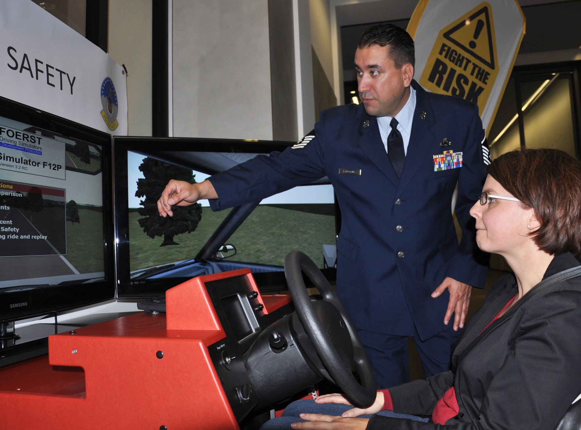 BERLIN-- Master Sgt. Victoriano Rodriguez, 52nd Fighter Wing traffic safety manager, shows Sandra Michel, Bundesrat employee, the side-view window display on a driving simulator Oct. 11 at the Bundesrat here. Members of 52nd FW safety office and members of the U.S. Army in Europe safety office traveled here to present “Fight the Risk,” a campaign for safe driving, for a health and wellness day for Bundesrat employees. The simulator was used in the demonstrations to give people the opportunity to test out various driving conditions to include: weather, location and driving under the influence.  After drivers go through a course, they are given a report on mistakes they made, such as missing a turn signal. (U.S. Air Force photo/ Senior Airman Natasha Stannard)