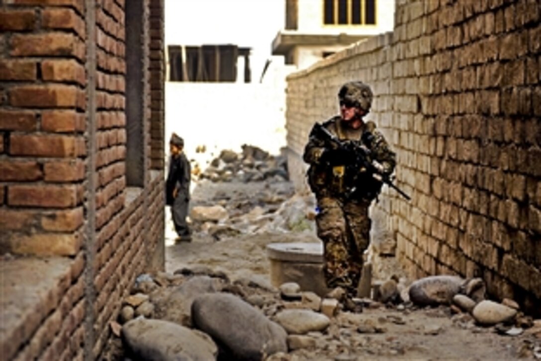 U.S. Army Sgt. Sean Matthews searches an alley while on a patrol in the Mehtar Lam district in Afghanistan's Laghman province, Oct. 8, 2011. Matthews is a team leader assigned to the Laghman Provincial Reconstruction Team, which visited with local leaders to discuss building a second orphanage for children who have lost their families.