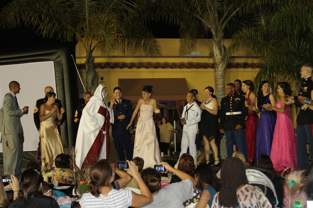 Men and women participate in a fashion show as part of the Marine Corps Community Services Ball Gown Giveaway sing and dance along with a Lady GaGa impersonator at the Bay View Restaurant aboard Marine Corps Recruit Depot San Diego. Volunteers modeled several of 1,500 ball gowns donated by San Diego women as participants enjoyed a complimentary dinner. All women who attended took home a free dress, a pair of shoes and an accessory. "We want the younger spouses to be able to come here and not feel intimidated while taking pressure off finding a gown for the ball," said Natalie Francisco, MCCS Marine Corps Family Team Building Director.