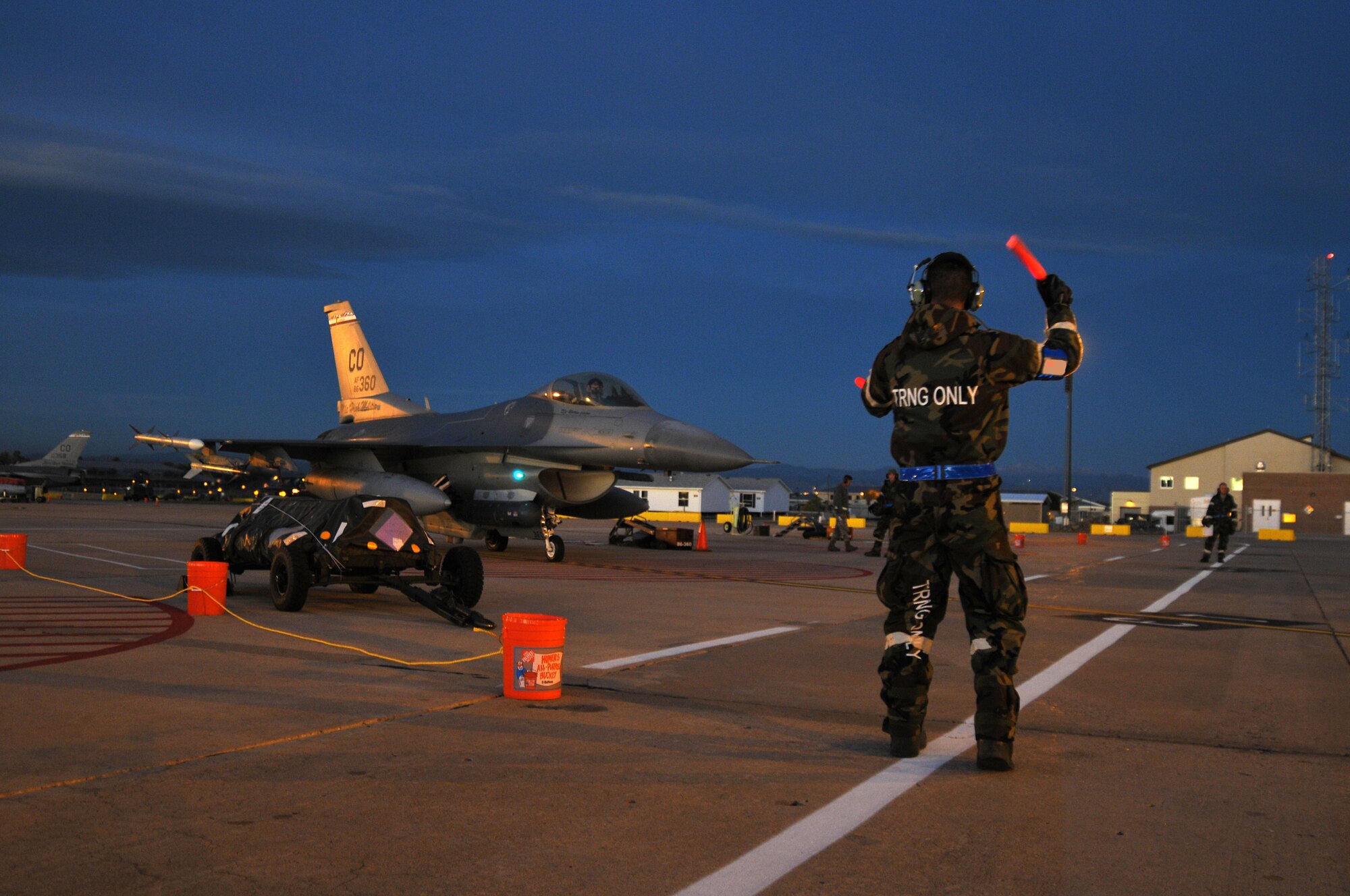 U.S. Air Force Senior Airman James Buchanan, 140th Aircraft Maintenance Squadron, marshals out an F-16 Fighting Falcon at the break of dawn during an Operational Readiness Exercise at Buckley Air Force Base Colo., October 15, 2011. Buckley Air National Guard airmen are taking part in the Operational Readiness Exercise being held on base throughout the weekend. The ORE evaluates airmen with mission readiness in preparation for real world deployments as well as next year’s Operational Readiness Inspection.  U.S. Air Force photo by: Wolfram M. Stumpf (RELEASED)