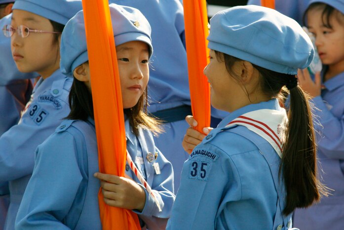 Two parade performers hold their banners during the opening ceremony at the 55th annual Iwakuni Festival Oct. 16 held in downtown Iwakuni. According to the event host, approximately 100,000 people permeated the streets of downtown Iwakuni to attend the festival, which was filled with live music, dancing, parades, vendors and food.::r::::n::