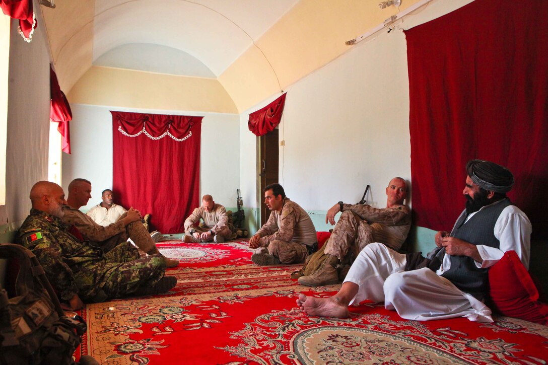 Afghan National Army Lt. Col. Gul Ahmad (left), the kandak commander of 1st Kandak, 1st Brigade, 215th Corps; and Mercer Island, Wash., native Lt. Col. Tyler Zagurski (second from left), the commanding officer of 1st Battalion, 9th Marine Regiment; relax in the home of Haji Janan (right).  Janan, a local elder, warmly invited the patrolling security forces for tea and fruit during their trek across the district.