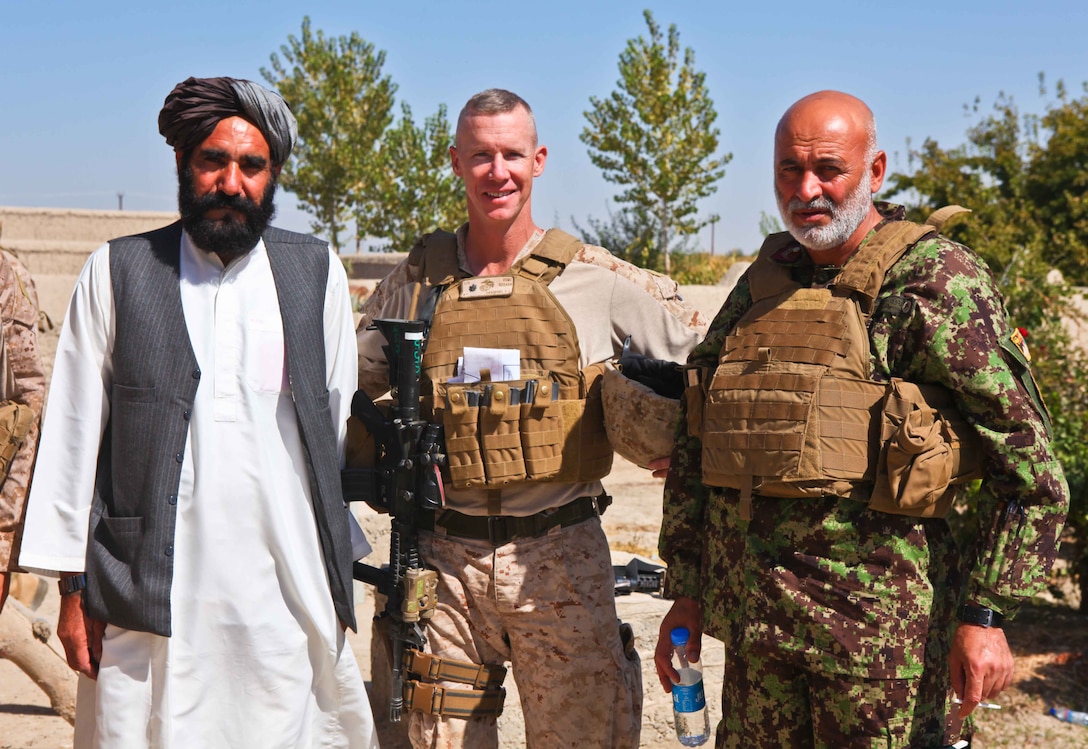 (From left) Local elder Haji Janan; Mercer Island, Wash., native Lt. Col. Tyler Zagurski the commanding officer of 1st Battalion, 9th Marine Regiment; and Afghan National Army Lt. Col. Gul Ahmad, the kandak commander of 1st Kandak, 1st Brigade, 215th Corps; pose for a photo outside Janan’s home.  During their visit, the officers spoke with Janan about local agriculture, security, and the great progress Nawa has made.