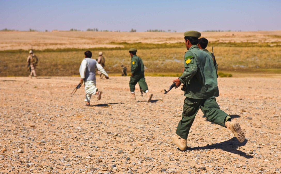Haji Hayatullah (dressed in white and gray), an Afghan Local Police commander leads ALP patrolmen toward gunfire in the desert surrounding Nawa.  During a patrol through the district, Afghan National Army soldiers and Marines with 1st Battalion, 9th Marine Regiment, heard an improvised explosive device detonate followed by machine-gun fire.  The group detoured from their route into the desert to determine the cause and lend aid if necessary.