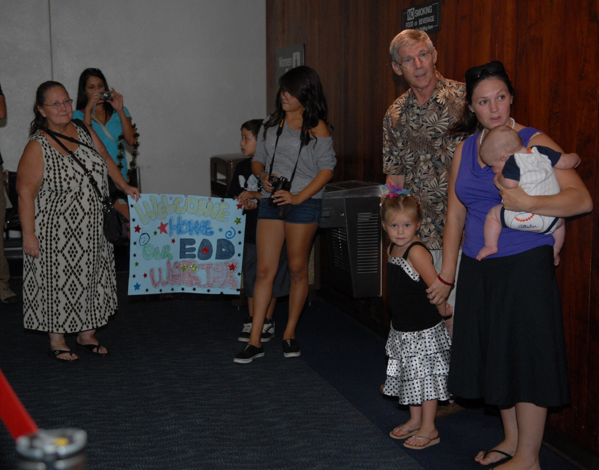 Family and friends wait for the arrival of Staff Sgt. DJ Dutton at the Honolulu International Airport Oct. 16 upon his return from a deployment to Afghanistan. Dutton, an explosive ordnance disposal technician deployed from the 647th Civil Engineer Squadron at Joint Base Pearl Harbor-Hickam, Hawaii, was wounded by an improvised explosive device Sept. 14 in Afghanistan. He was treated at Brooks Army Medical Center, Texas, before returning to his wife, Stacy (pictured), and two children. (U.S. Air Force photo by Staff Sgt. Carolyn Herrick)