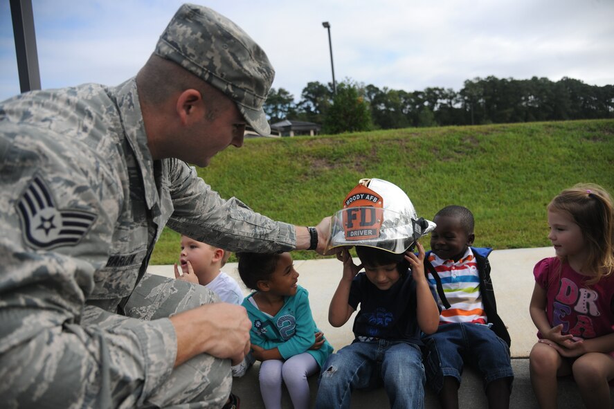 U.S. Air Force Staff Sgt. Eric Barlow, 23rd Civil Engineer Squadron firefighter, interacts with children from the Child Development Center II by letting them try on a fire helmet at Moody Air Force Base, Ga., Oct. 13, 2011. Barlow and fellow firefighters visited the CDC II to give the children a tour of their fire truck and promote fire safety as a part of National Fire Prevention Week. (U.S. Air Force photo by Airman 1st Class Paul Francis/Released)
