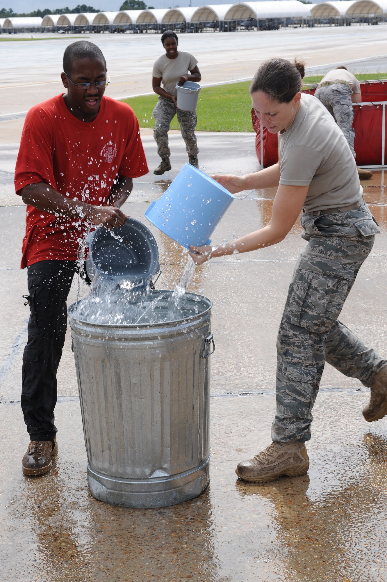 Airmen from the 23rd Security Forces Squadron pour buckets of water into an aluminum trashcan during a Fire Muster Challenge at Moody Air Force Base, Ga., Oct. 11, 2011. The challenge took place in support of National Fire Prevention Week, a week focused on promoting fire safety and prevention. (U.S. Air Force photo by Senior Airman Ciara Wymbs/Released) 