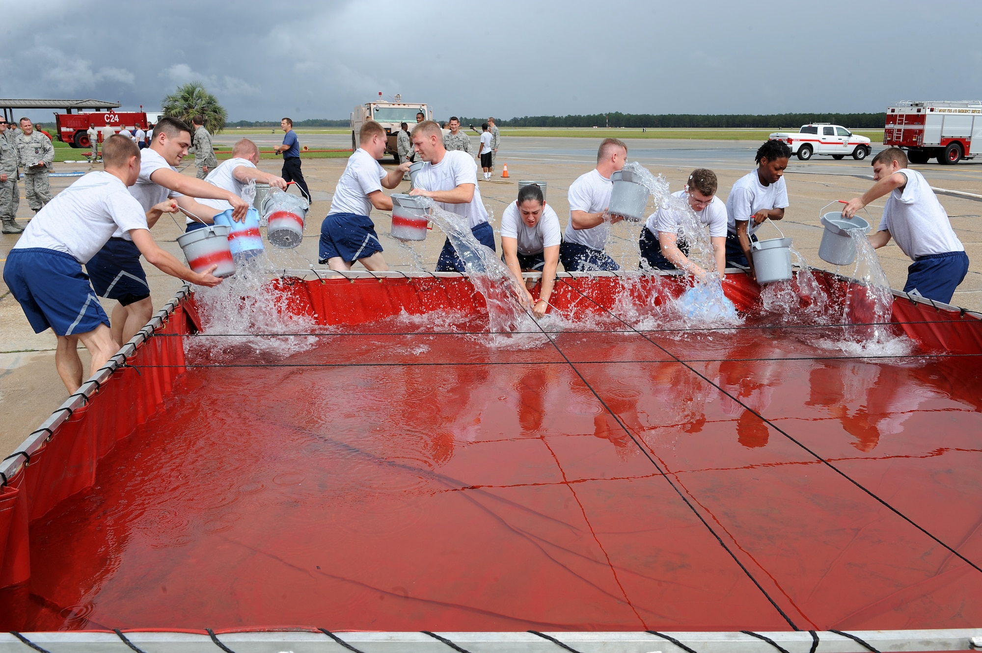Teams of airmen fill buckets with water from a storage pool during the bucket brigade portion of a Fire Muster Challenge at Moody Air Force Base, Ga., Oct. 11, 2011. The teams had to use the buckets of water to fill an aluminum can, staged 25 feet away. The cumulative time for completing all activities determined the winner (U.S. Air Force photo by Senior Airman Ciara Wymbs/Released) 