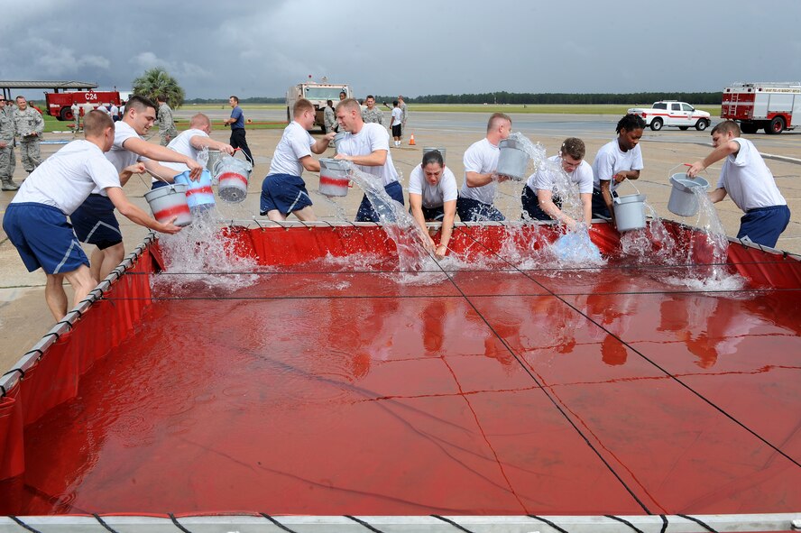 Teams of airmen fill buckets with water from a storage pool during the bucket brigade portion of a Fire Muster Challenge at Moody Air Force Base, Ga., Oct. 11, 2011. The teams had to use the buckets of water to fill an aluminum can, staged 25 feet away. The cumulative time for completing all activities determined the winner (U.S. Air Force photo by Senior Airman Ciara Wymbs/Released) 