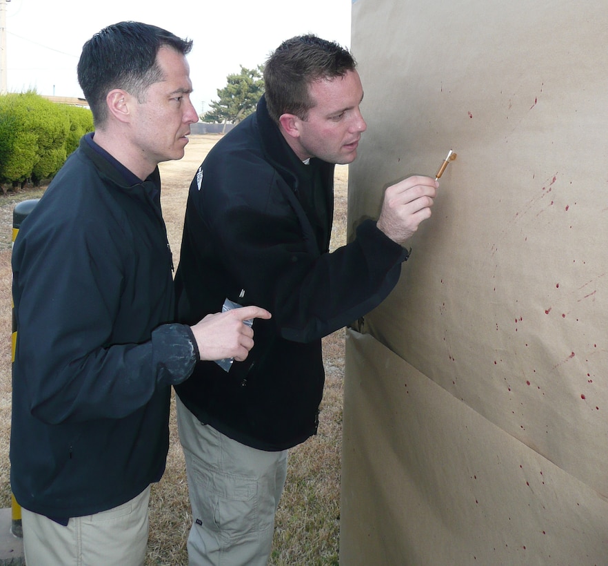 AFOSI agents take blood samples from a wall during a forensic training exercise. (Air Force Photo)