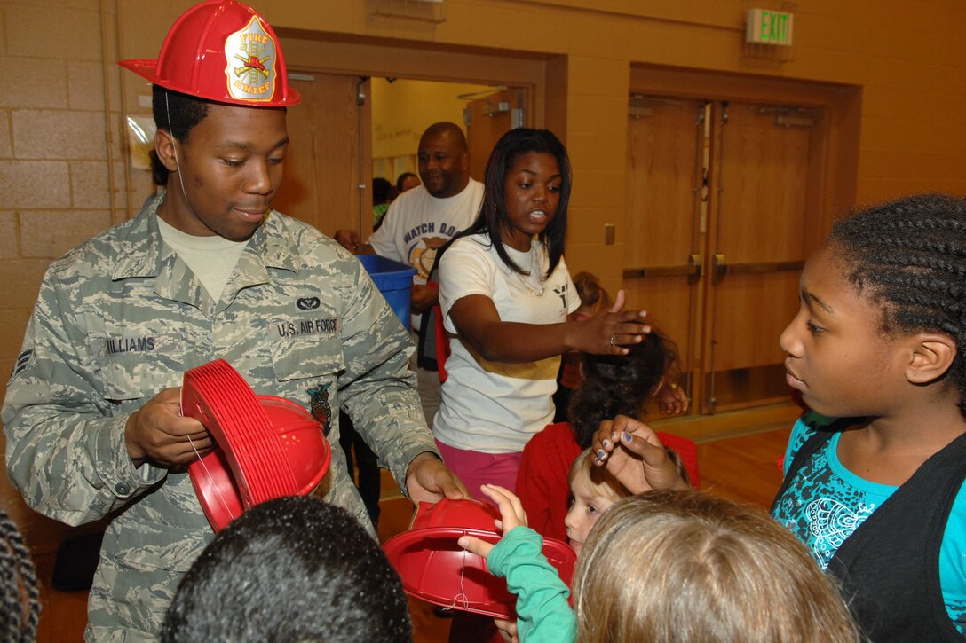 U.S. Air Force Senior Airman Anthoney Williams, 633d Civil Engineer Squadron firefighter, hands out fire prevention items to children at the Bethel Manor Youth Centerduring a National Fire Prevention Week assembly at Langley Air Force Base, Va., Oct. 13, 2011. This year’s National Fire Prevention week theme is “Protect Your Family from Fire,” and the children learned the importance of dialing 911 in an emergency. (U.S. Air Force photo by Staff Sgt. Jeff Nevison/Released)