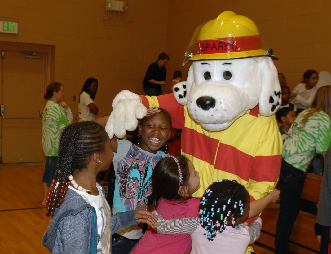 Children hug Sparky the Fire Dog during a National Fire Prevention Week assembly at the Bethel Manor Youth Center at Langley Air Force Base, Va., Oct. 13, 2011. The 633d Civil Engineer Squadron introduced Sparky 60 years ago to teach children good fire prevention habits during National Fire Prevention Week. (U.S. Air Force photo by Staff Sgt. Jeff Nevison/Released)