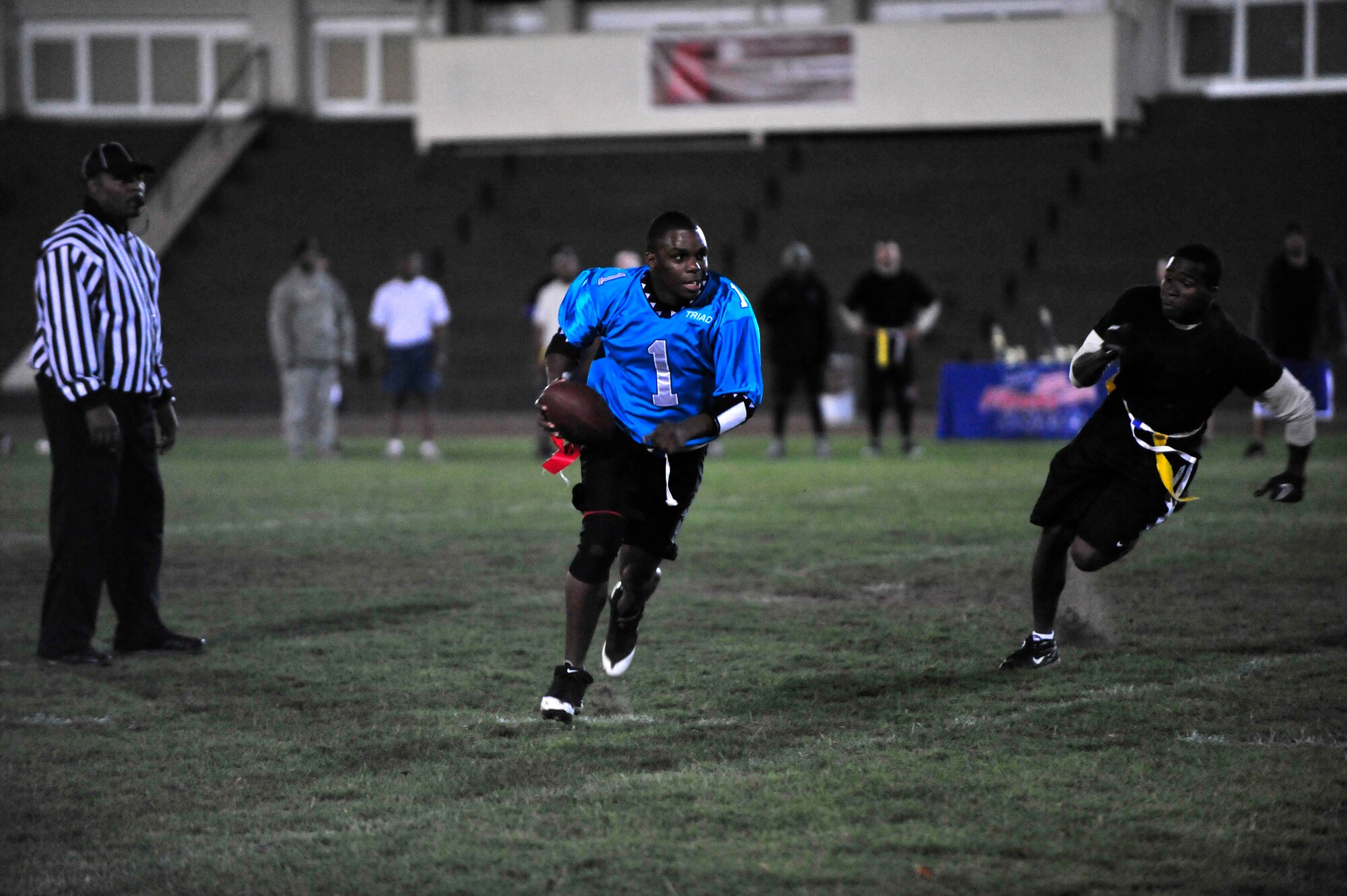 Tech. Sgt. Ivan Thomas, Team Triad quarterback, runs the ball while Airman 1st Class Johnny Harris, 86th Security Forces, tries to catch him during the flag football championship game, Vogelweh track field, Vogelweh Military Complex, Oct. 14, 2011.  Team Triad won 21 games straight seizing an undefeated title and closed the season with one more win against SFS 21-0.  (U.S. Air Force Photo by Tech. Sgt. Chenzira Mallory)