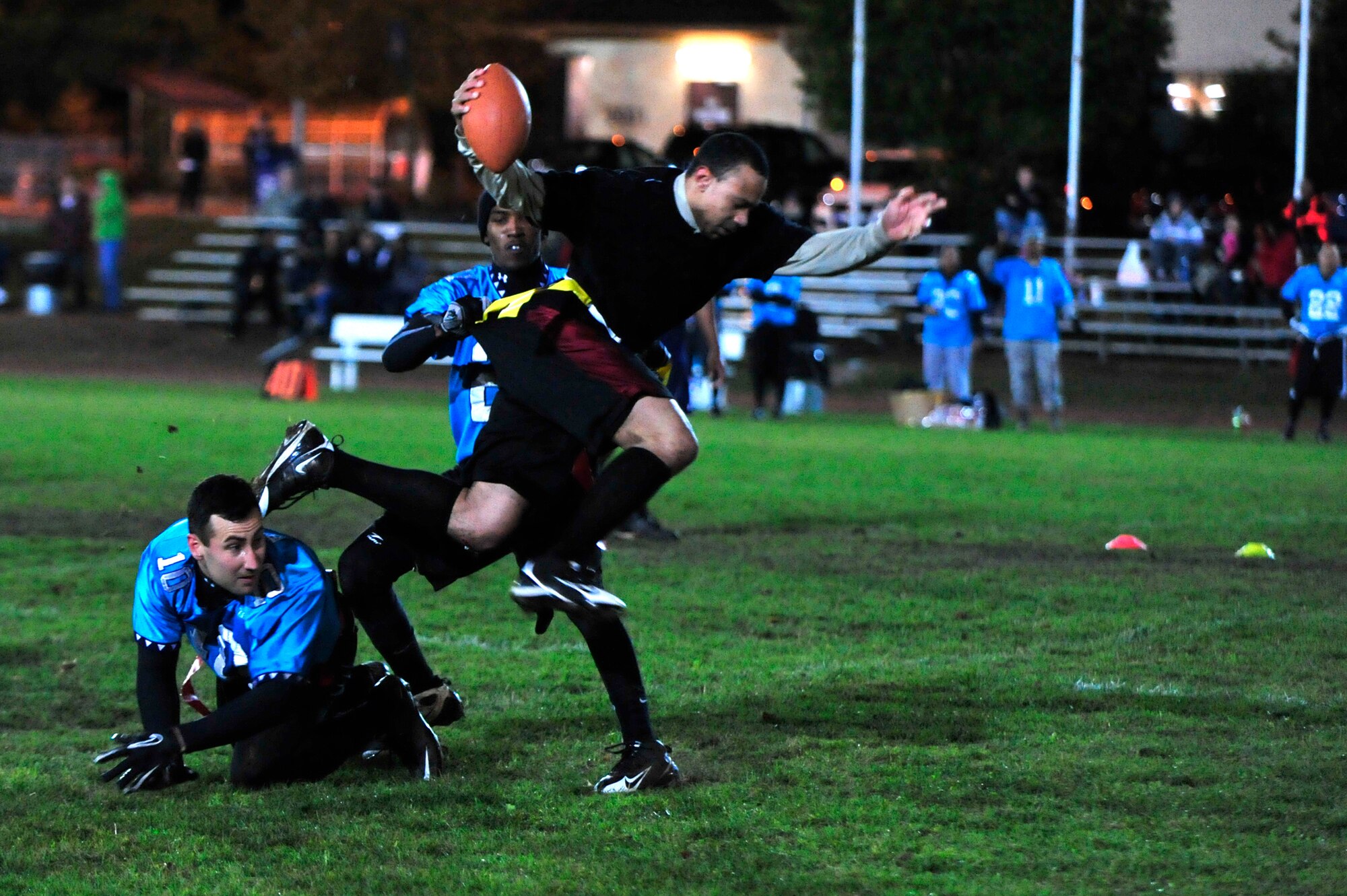 Airman 1st Class Christopher Piro and Senior Airman Jeremy Marshall, both 1st Air and Space Communications Operations Squadron and Team Triad, try and take the flag from Senior Airman Roderick Green, 86th Security Forces, during the flag football championship game, Vogelweh track field, Vogelweh Military Complex, Oct. 14, 2011.  Team Triad won 21 games straight seizing an undefeated title and closed the season with one more win against SFS 21-0.  (U.S. Air Force Photo by Tech. Sgt. Chenzira Mallory)