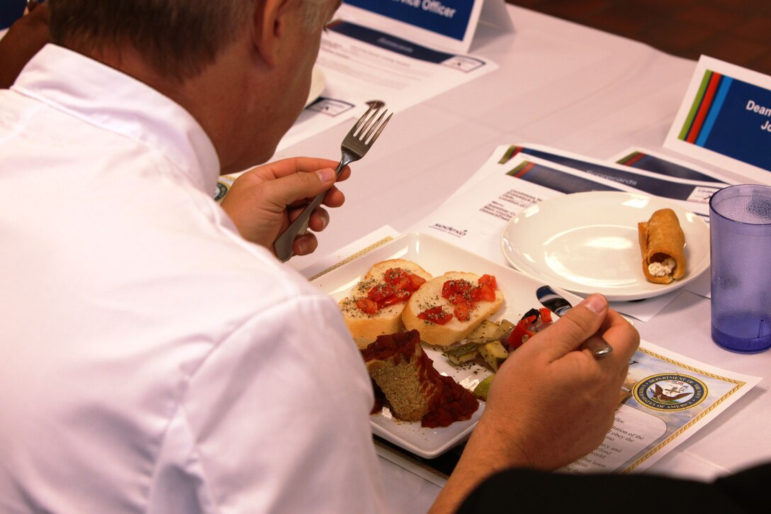 A judge samples a dish cooked by Marine and civilian food service specialists who participated in the third quarter Culinary Team of the Quarter competition at Mess Hall 411 abaord Marine Corps Base Camp Lejeune, Oct. 18.