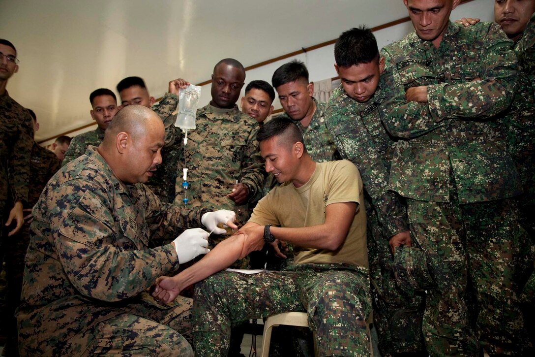 U.S. Navy Chief Petty Officer Edmond Reyes, 31st Marine Expeditionary Unit, III Marine Expeditionary Force demonstrates how to give an intravenous solution to Philippine Marines and Sailors taking a combat life savers course at Naval Forces West, Naval Station Carlito Cunanan, Ulugan, Palawan, The Republic of the Philippines, Oct. 18, 2011. The training was a part of Phiblex 2012, an exercise intended to maintain readiness and interoperability between the Government of the Republic of the Philippines and the U.S. (U.S. Marine Corps photo by Cpl. Patricia D. Lockhart)