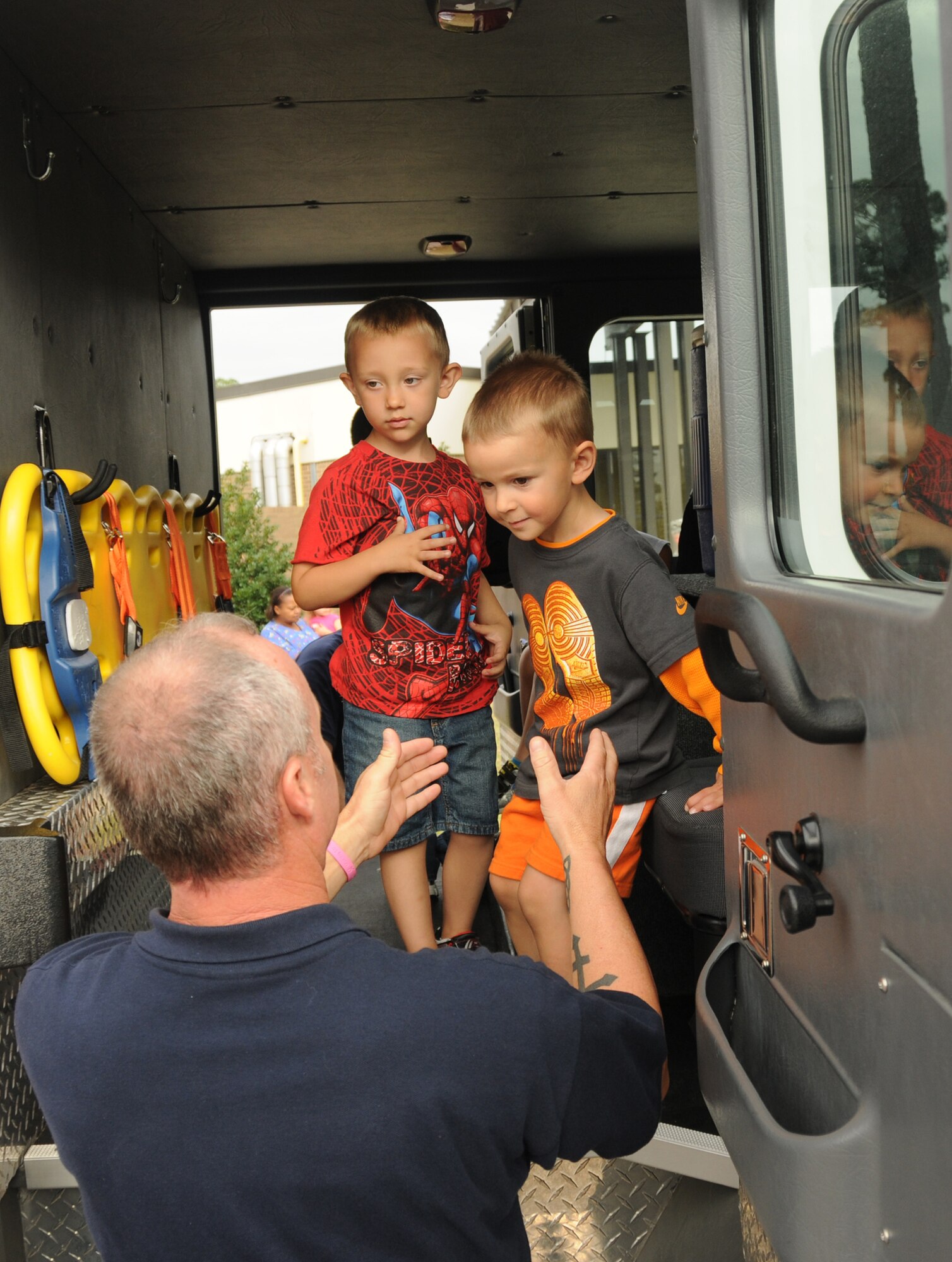 Troy Smith, 81st Infrastructure Division, Keesler firefighter, gives assistance to Riley Cavett, 4, and Shaun Sullivan, 3, during their tour of a fire truck Oct. 12, 2011.  Members of the Keesler fire Department visited the Child Development Center at Keesler Air Force Base, Miss., as part of Fire Prevention week which was held Oct. 11-15.  Riley is the son of Staff Sgt. Chonal Cavett, 335th Training Squadron.  Shaun’s parents are Tech. Sgt. Shane and Christy Sullivan, 81st Training Wing.  (U.S. Air Force photo by Kemberly Groue)