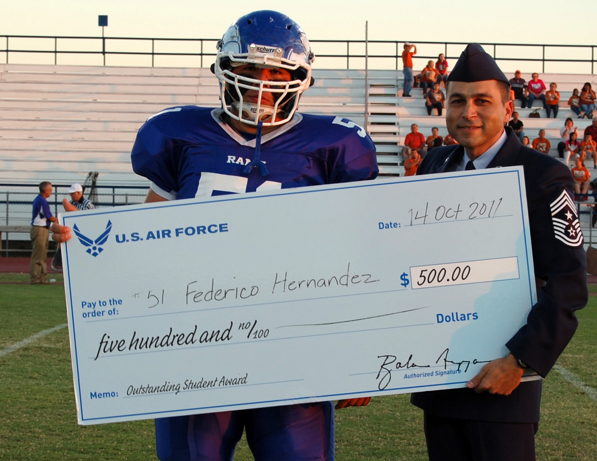 LAUGHLIN AIR FORCE BASE, Texas - Chief Master Sgt. Ruben Gonzalez, Air Force Personnel Center command chief, presents a scholarship at the Walter Levermann Ram Stadium, Del Rio, Oct. 14 to Federico Hernandez, Del Rio Rams. The scholarship is intended to help student athletes toward their college education. (U.S. Air Force photo/Master Sgt. Peter Borys)