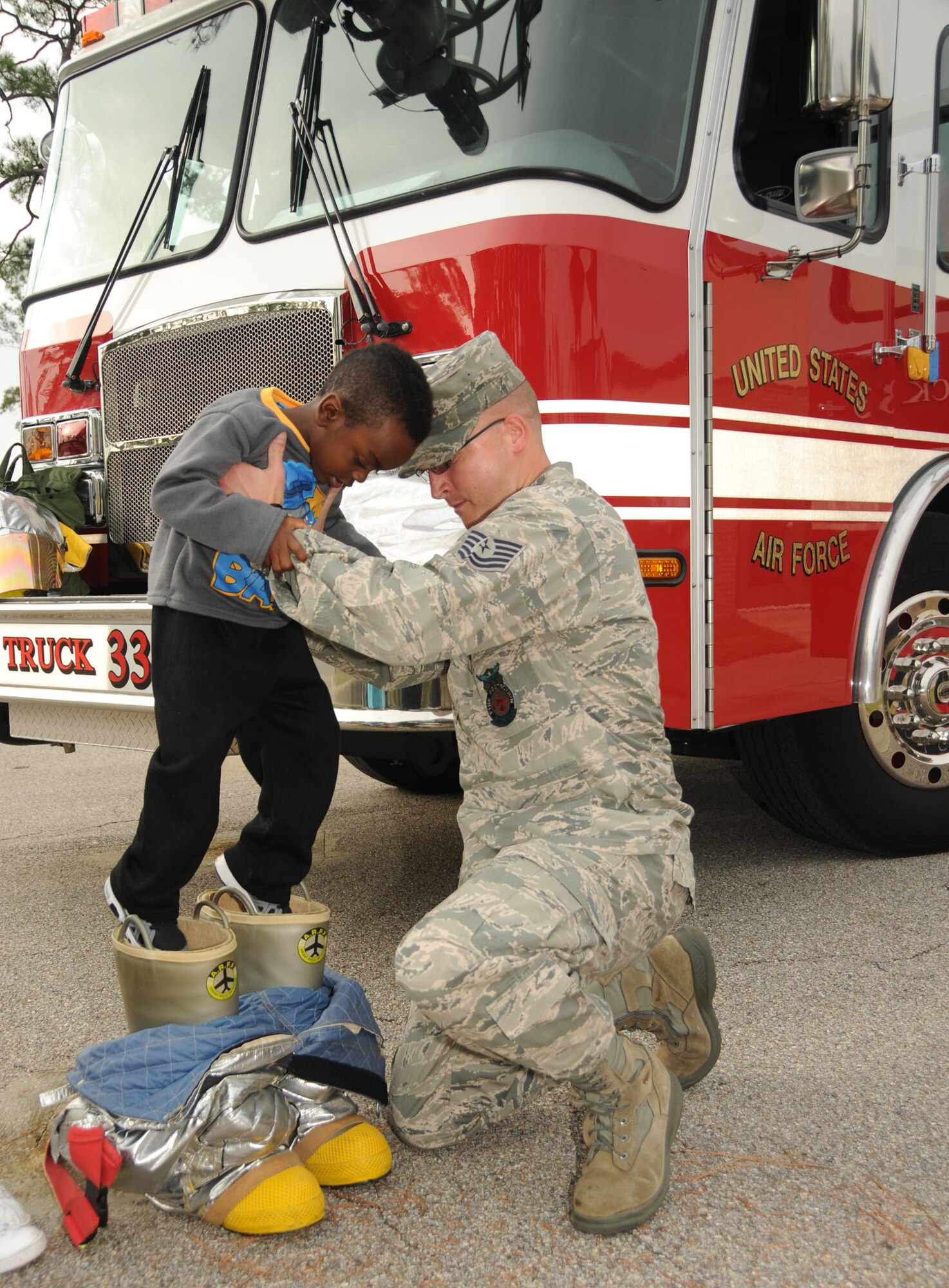 Malachi Davis, 4, son of Tech. Sgt. Dorothy Davis, 334th Training Squadron, is carefully placed in a pair of fire bunkers by Tech. Sgt. Daniel Blankenship, 81st Infrastructure Division Fire Inspector during a visit by members of Keesler Fire Department Oct. 12, 2011, at Keesler Air Force Base, Miss.  Fire Prevention week was held Oct. 11-15.  (U.S. Air Force photo by Kemberly Groue)