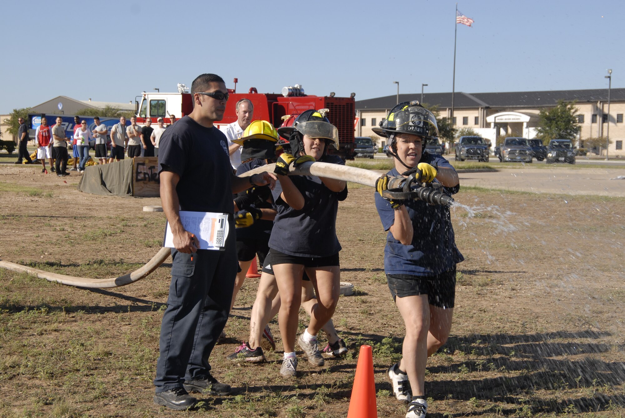 GOODFELLOW AIR FORCE BASE, Texas – A team of firefighter spouses lead by Stephanie Kammer, spray a water hose to knock down a target during a firefighter competition muster here Oct. 14. The fire department hosted the competition as part of the 89th National Fire Prevention Week, and to help raise awareness of fire safety. (U.S. Air Force photo /Senior Airman Heather L. Rodgers)