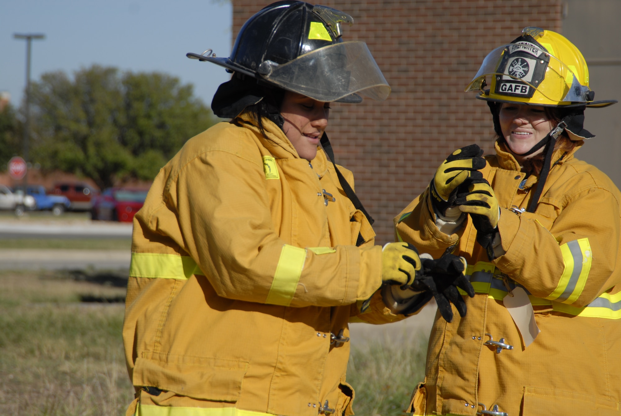GOODFELLOW AIR FORCE BASE, Texas – From left, Danielle Mora and Tiffany Hebert, spouses of Goodfellow firefighters, don fire fighting suits during a firefighter competition muster here Oct. 14. The fire department hosted the competition as part of the 89th National Fire Prevention Week, and to help raise awareness of fire safety. (U.S. Air Force photo /Senior Airman Heather L. Rodgers)