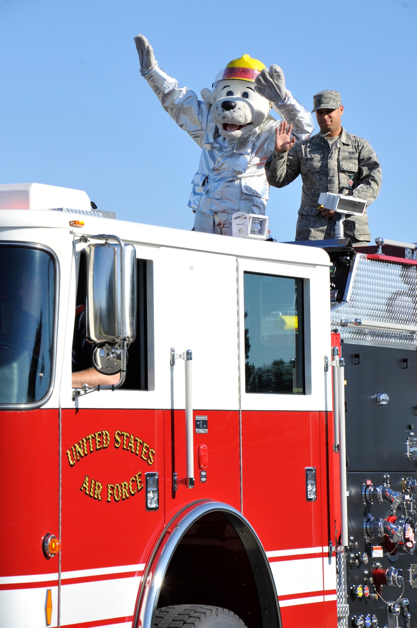 Airman 1st Class Darren Ortiz and Sparky wave to Team Dover Oct. 15, 2011, as they parade through the streets of Dover Air Force Base, Del., family housing. The parade was part of the National Fire Protection Agency's Fire Prevention Week, which ran from Oct. 8 - 15. (U.S. Air Force photo by Tech. Sgt. Charles Walker)