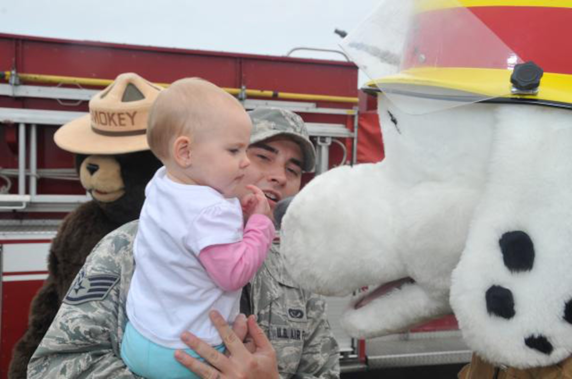 Allison Varchetto plays with Sparky the fire dog while her father, Staff Sgt. Matthew Varchetto, watches during the Fire Prevention Week kick-off Oct. 11, 2011, at Dover Air Force Base, Del. The theme for this year's Fire Prevention Week was family-fire safety. (U.S. Air Force photo by Tech. Sgt. Charles Walker)