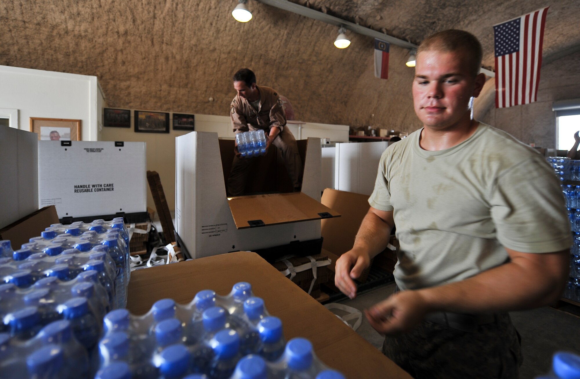 Capt. Jeremy Stuursma (background), 340th Expeditionary Air Refueling Squadron pilot and volunteer, and Spc. Shayne McKeever, 824th Quartermaster Company Det.10 Rigger, pack cases of water onto a pallet, Oct. 14. Army Riggers pack pallets of supplies for air-drop to forward operating bases across the Area of Responsibility. The Riggers accept volunteers to help them pack the pallets with food, water, fuel or other supplies that may be needed. Stuursma, a native of Tinley Park, Ill., is deployed from McConnell Air Force Base, Kan. McKeever, a native of Elizabethtown, Ky., is deployed from the U.S. Army Reserve’s 861st Quartermaster Company in Nashville, Tenn. (U.S. Air Force photo/Senior Airman Paul Labbe) 