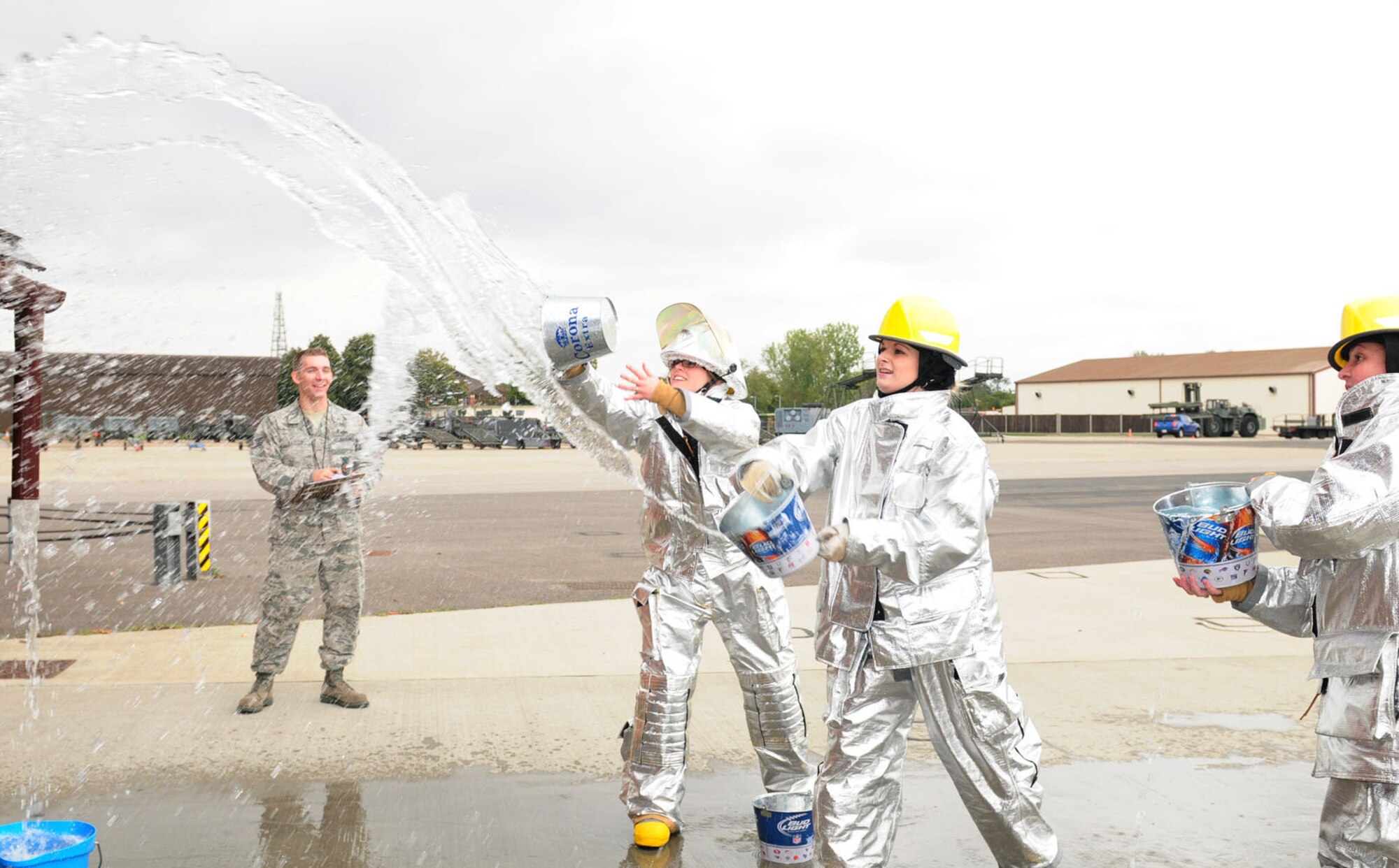 RAF MILDENHALL, England -- The only all-female team, 100th Force Support Squadron Civilian Personnel Flight ‘CPF Belles,’ throw buckets of water over a mock house as Staff Sgt. Noah Leiter, 100th Civil Engineer Squadron Fire Department, keeps time and score at the fire muster at the RAF Mildenhall Fire Department Oct. 13, 2011. Five teams competed in the Fire Prevention Week events. (U.S. Air Force photo/Karen Abeyasekere)