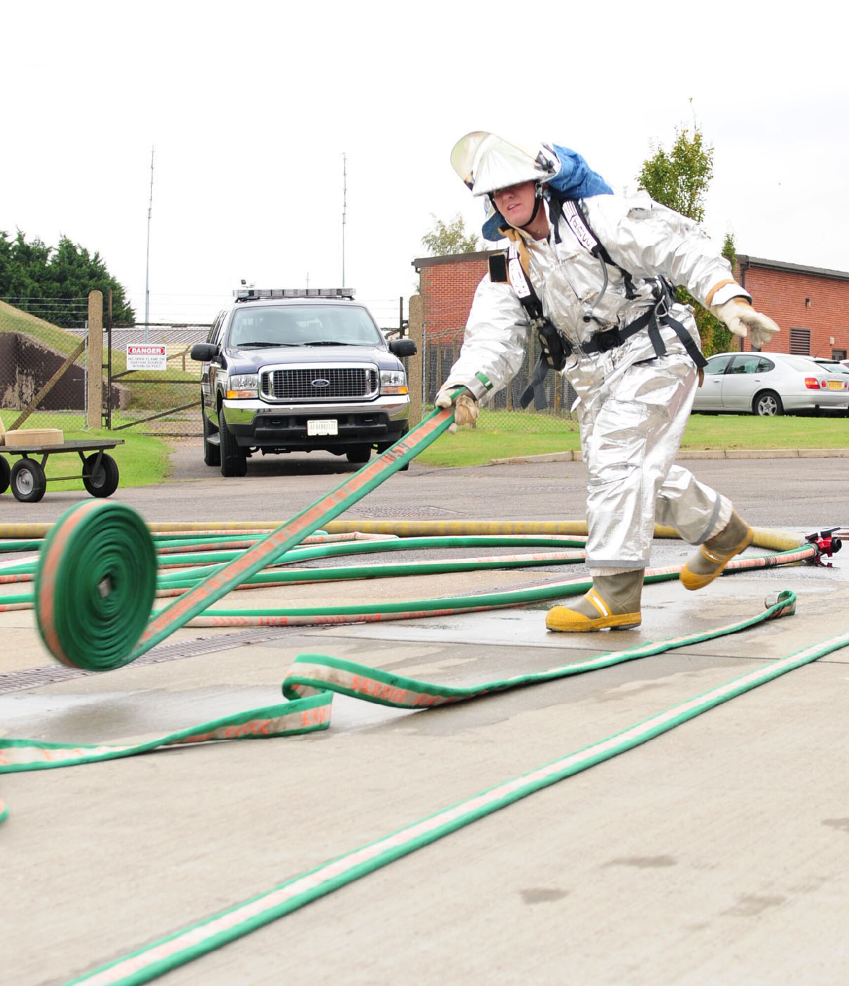 RAF MILDENHALL, England -- Airman 1st Class Ryan Riniker, 100th Logistics Readiness Squadron ‘Team Vehicle Maintenance 2’ member, throws a hose out to unroll it before joining it to other hoses and discharging water during the hose connection event at a fire muster here Oct. 13, 2011. The fire muster was part of Fire Prevention Week events and consisted of five teams going through 10 stations while dressed in firefighter gear. (U.S. Air Force photo/Karen Abeyasekere)