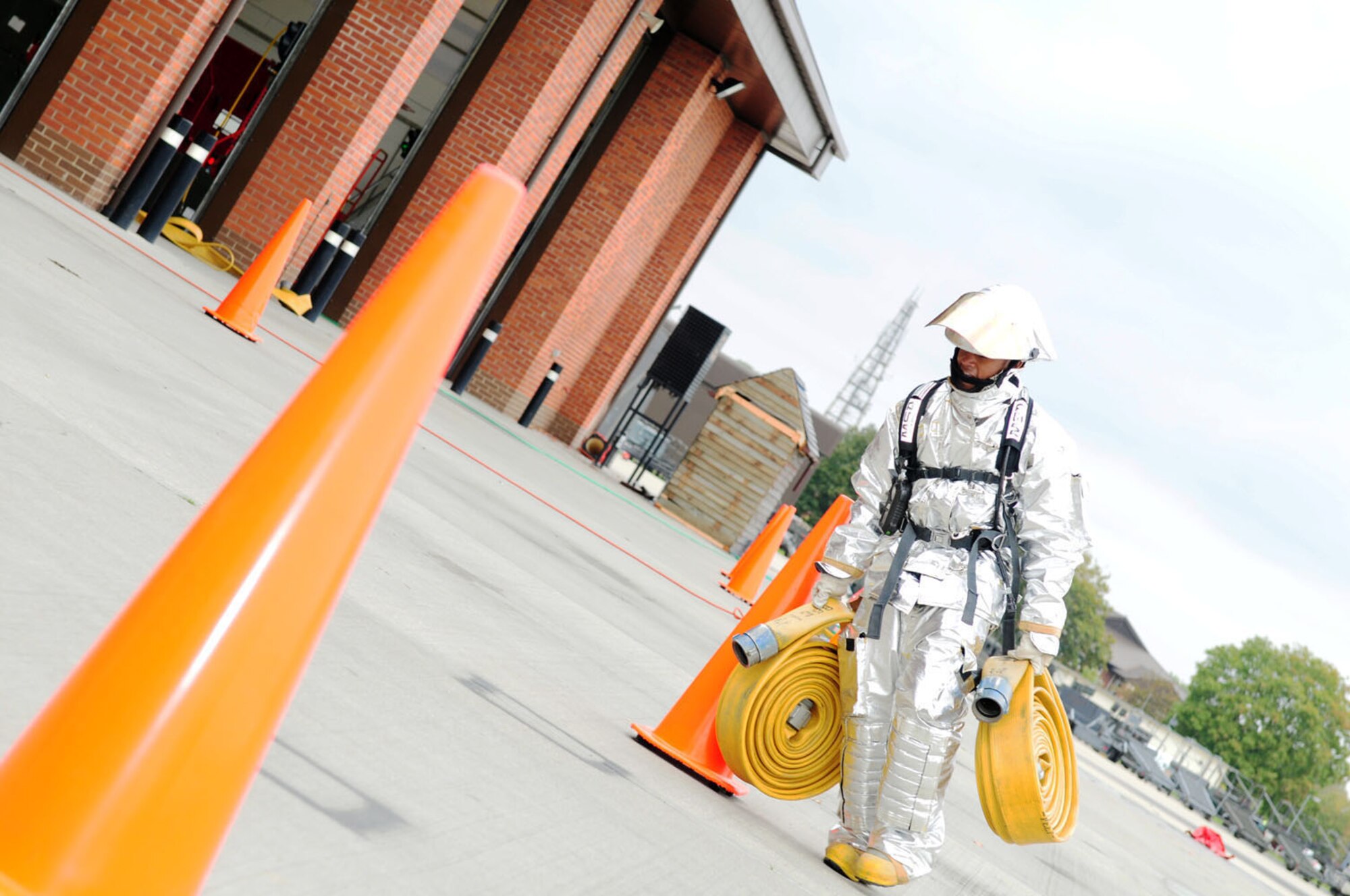RAF MILDENHALL, England -- Airman 1st Class Brandon Lightner, 100th Logistics Readiness Squadron ‘Team Vehicle Maintenance 2’ member, runs between cones while carrying two rolled fire hoses at the fire muster Oct. 13, 2011, at the fire department here. The fire muster was part of Fire Prevention Week events and five teams competed in the event, which consisted of stations including bunker drill, hose pull, rescue mannequin, hose connection and bucket brigade. (U.S. Air Force photo/Karen Abeyasekere)