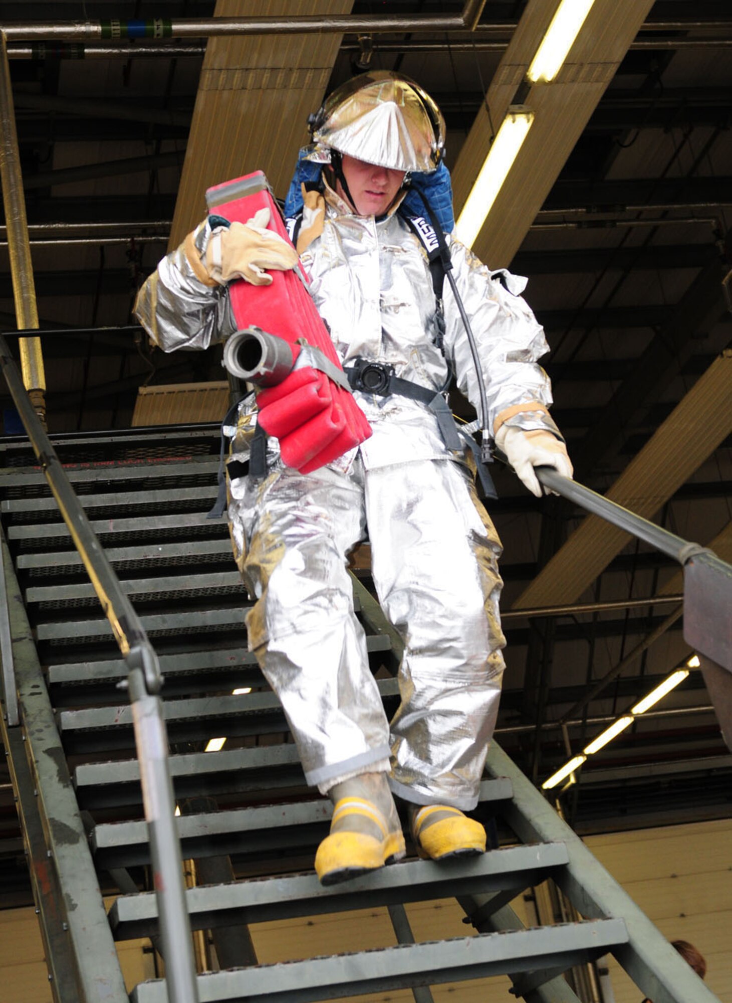RAF MILDENHALL, England -- Airman 1st Class Ryan Riniker, 100th Logistics Readiness Squadron ‘Team Vehicle Maintenance 2’ member, moves quickly down the stairs while carrying a hose pack during the fire muster Oct. 13, 2011, at the fire department here. Five teams participated in events consisting of a bunker drill, hose drill, Keiser sled, dry hose advancement, mannequin rescue, stairs (carrying hose pack), hose connection, run, hose pull and charged line advancement. (U.S. Air Force photo/Karen Abeyasekere)