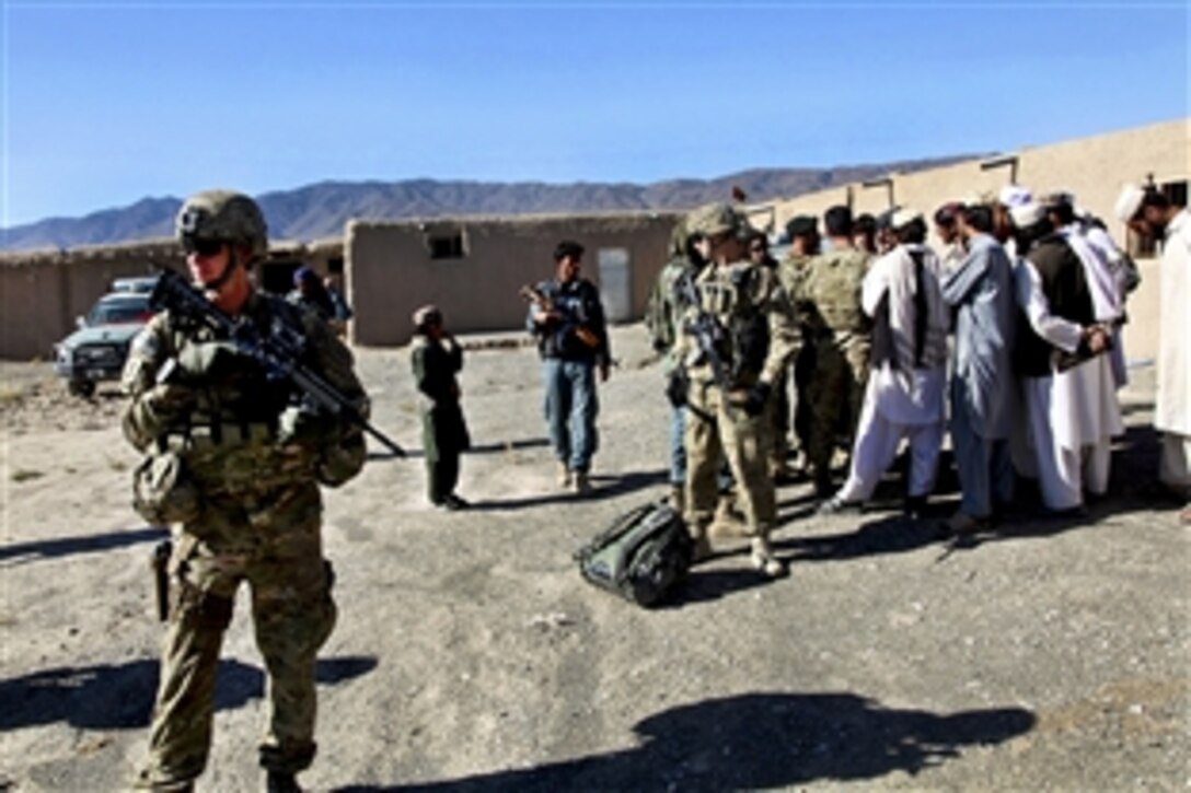 U.S. Army Capt. Tim Black, left, helps provide security while Afghan and coalition leaders speak with village elders from the Sahak Triangle area in the Zormat district in Afghanistan's Paktya province, Oct. 17, 2011. Black is a intelligence officer.