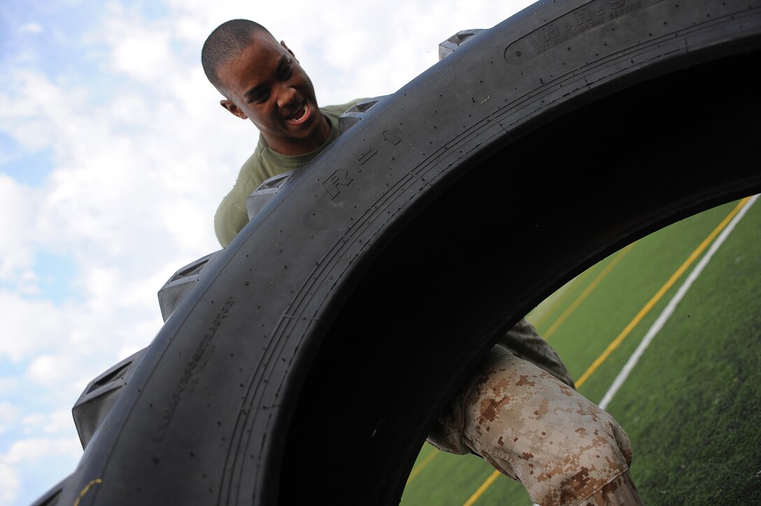 Lance Cpl. Carlton Williams, a member of the Marine Corps Silent Drill Platoon, flips a 100-pound tire in the sixth timed event of Musclefest at Marine Barracks Washington Oct. 18, 2011. For this part of the competition, Marines had to continuously flip a tire for 40 yards.