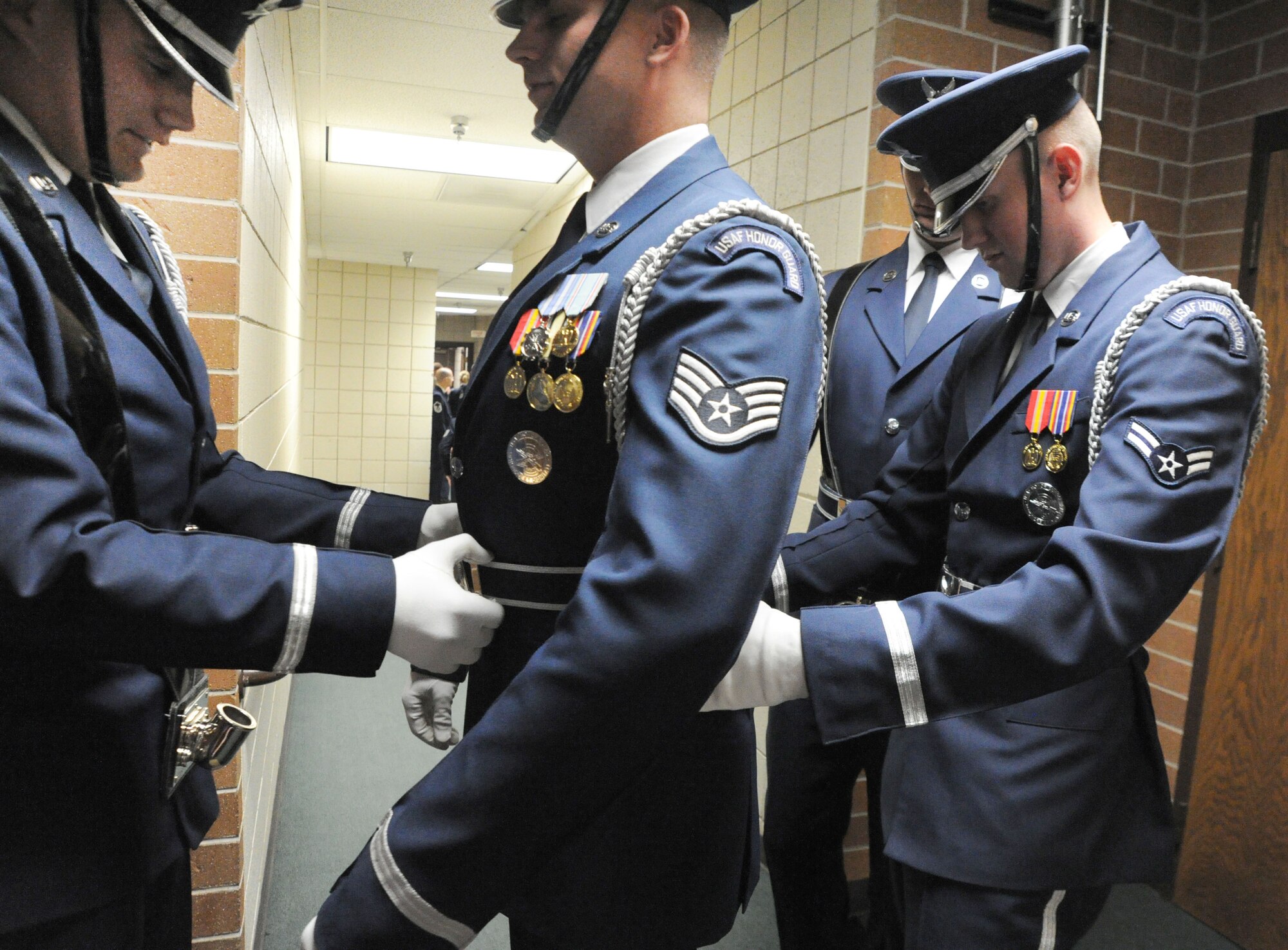 The U.S. Air Force Honor Guard Colors Team assists Staff Sgt. Jon Van Deusen, noncommisioned officer in charge of colors training, in preparing his uniform before entering the stage Oct. 18 at the Cheyenne Civic Center, Cheyenne, Wy. The colors team travels with the U.S. Air Force Band on their 25-day community relations tour across Montana, Wyoming, Nebraska, South Dakota. (U.S. Air Force photo by Airman 1st Class Tabitha N. Haynes)