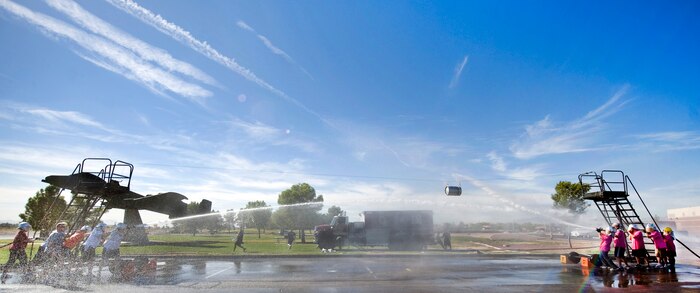 The 99th Air Base Wing Legal Office team faces off against the 99th Air Base Wing Public Affairs Photo Lab team during the fifth annual fire muster competition water hose tug-a-war Oct. 14, 2011, at Freedom Park on Nellis Air Force Base, Nev. The water hose tug-a-war involves a metal barrel being suspended on a cable as the two opposing teams try to move it to the opposite end of the cable using a highly pressurized fire hose. (U.S. Air Force photo by Lawrence Crespo) 
