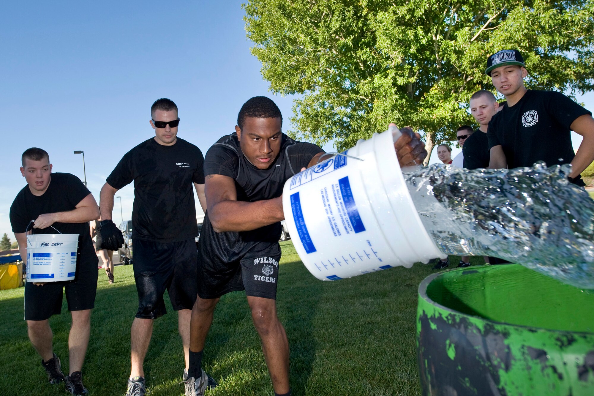 Left to right, Airman 1st Class Kyle Simpson, Staff Sgt. Jeremy Banfield and Airman 1st Class Mitchell Hood, 99th Logistic Readiness Squadron Fuels Management Flight technicians, pour buckets of water into a 55-gallon drum during the fifth annual fire muster competition Oct. 14, 2011, at Freedom Park on Nellis Air Force Base, Nev.  All three Airmen participated in the bucket brigade event against other Nellis teams. (U.S. Air Force photo by Lawrence Crespo) 