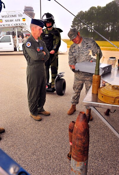 U.S. Air Force Tech. Sgt. Alex Rodriguez and Staff Sgt. Chandler Boettcher, 20th Civil Engineer Squadron explosive ordinance disposal technicians, demonstrate to Gen. Michael Hostage, Air Combat Command commander, the different types of equipment they use in the field with mobile transportation, at Shaw Air Force Base, S.C. Oct. 18, 2011. Displayed on the table and ground are different unexploded ordinances that may be used against our forces overseas.  (U.S. Air Force photo/Airman 1st Class Neil D. Warner)